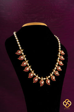 Necklace with pink and gold accents on a black mannequin against a purple background